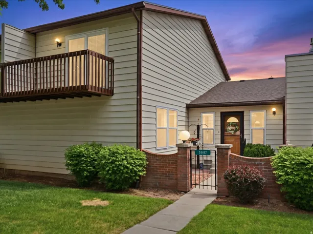 Entryway featuring a decorative iron gate, brick privacy wall, and an arched front door