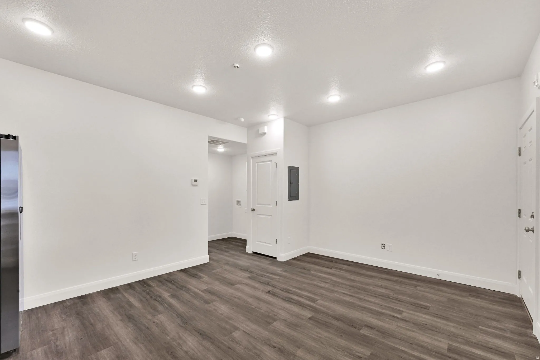Open-concept living area with wood-finish flooring, white walls, and recessed lighting