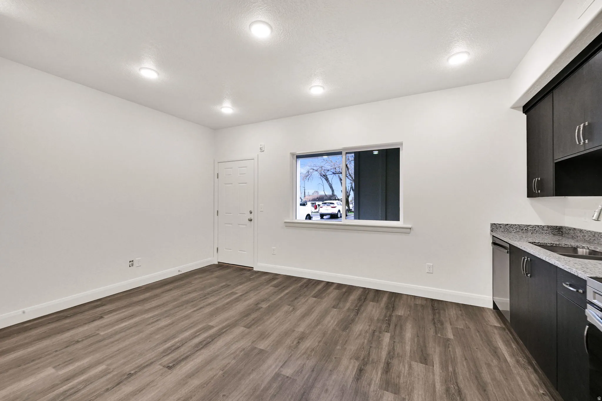 Open-concept living space featuring wood-finish flooring, recessed lighting, and white walls