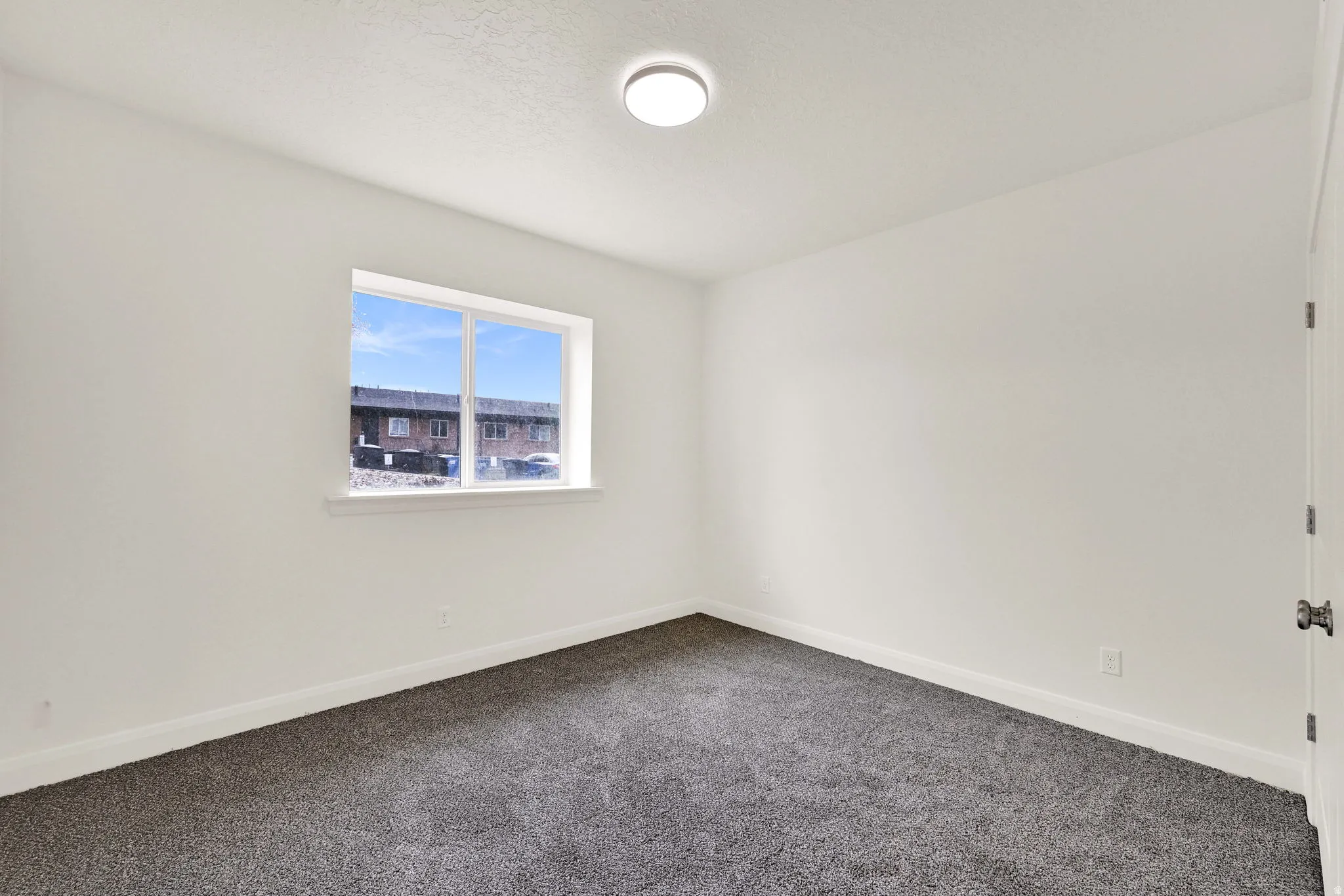 Room featuring a double-pane window, neutral white walls, dark gray carpeting, and white baseboards