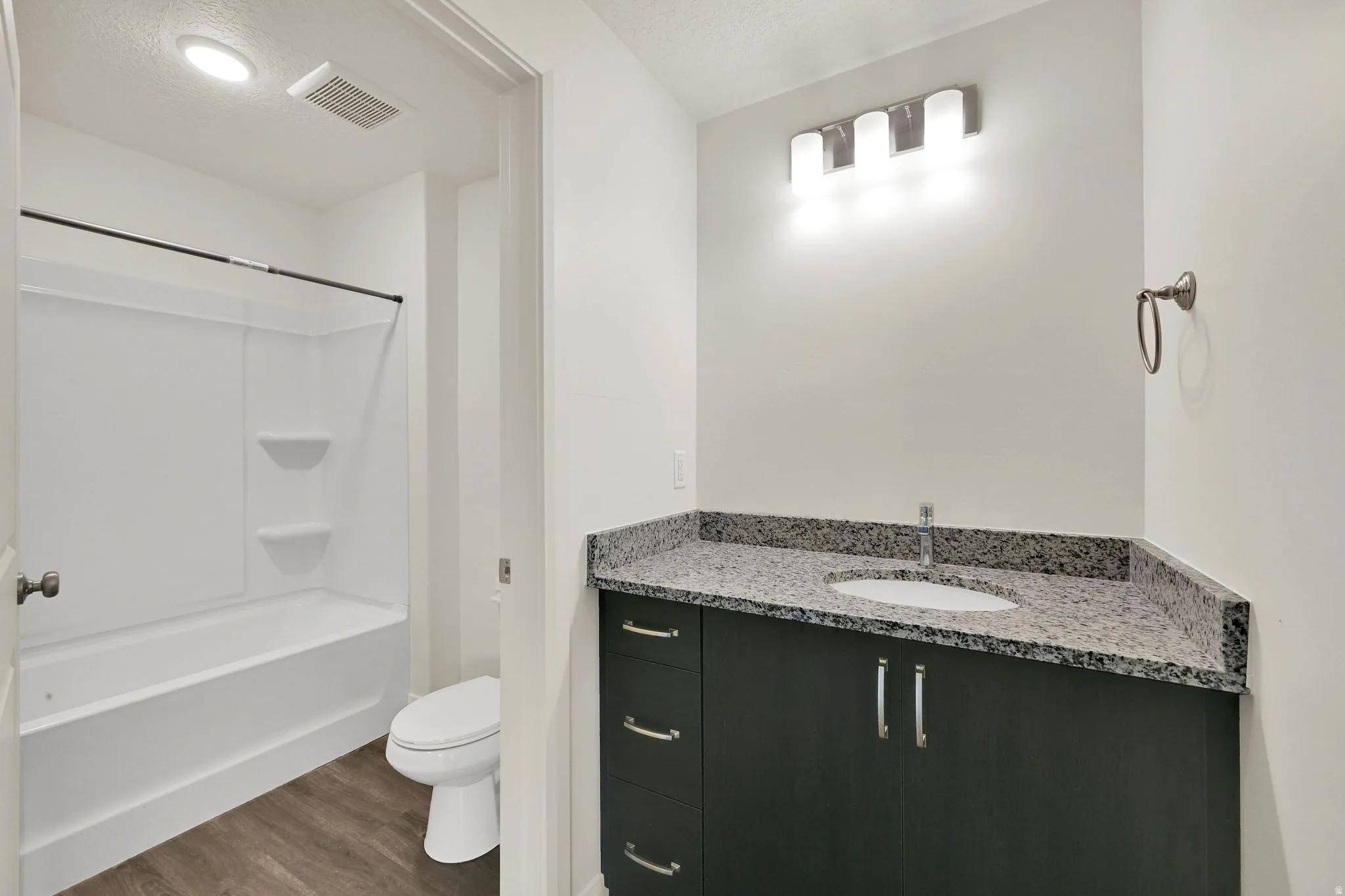 Bathroom featuring a dark wood-finish vanity with a granite-style countertop, undermount sink, and brushed nickel hardware