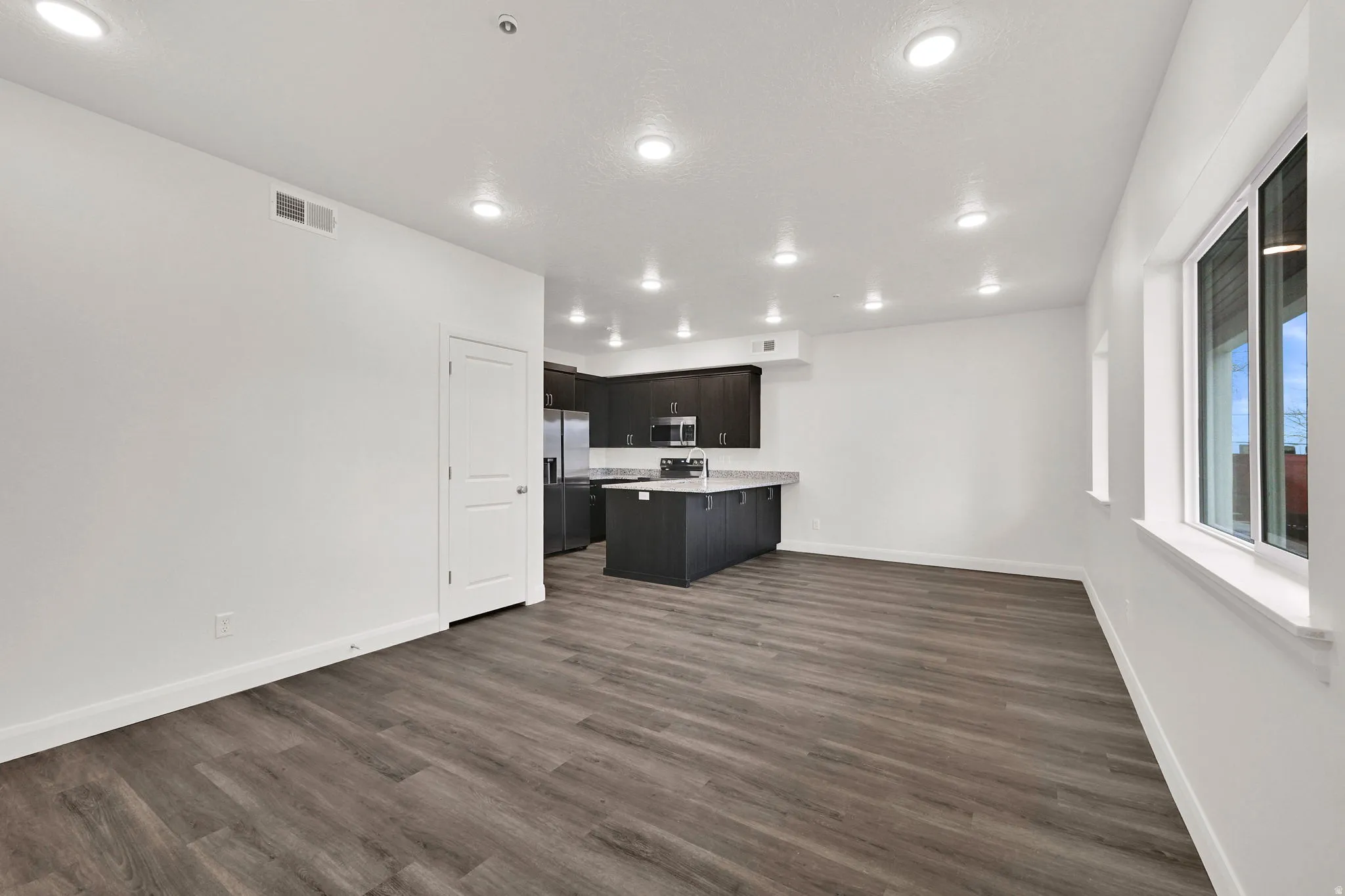 Open-concept living space featuring wood-finish flooring, recessed lighting, and white trim