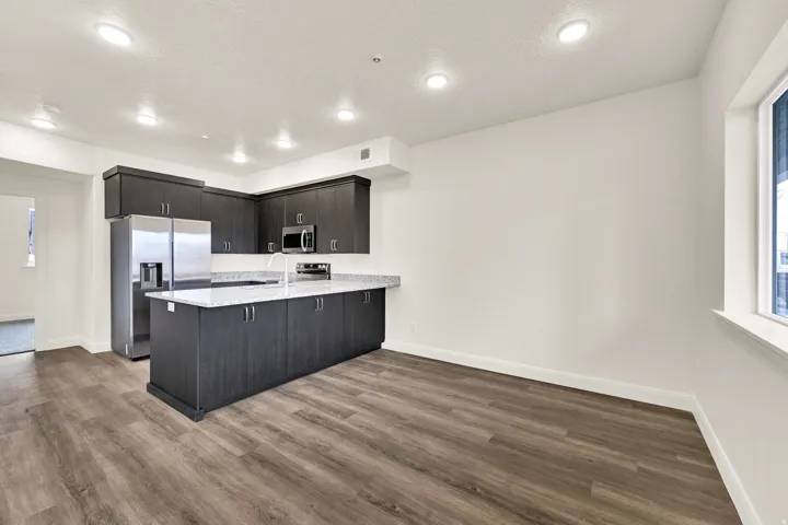 Modern kitchen featuring dark wood-finish cabinetry and an island with a white speckled countertop