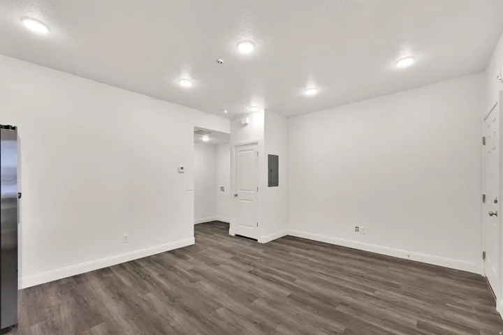 Open-concept living area with wood-finish flooring, white walls, and recessed lighting