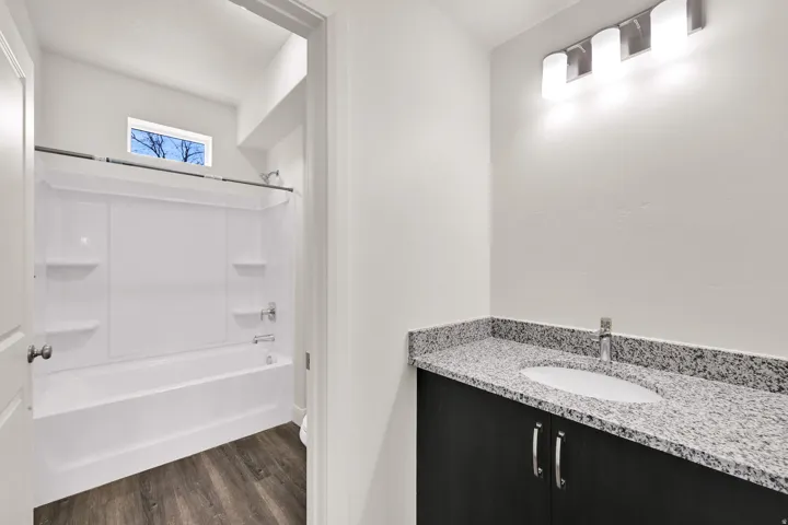 Bathroom featuring a dark wood-finish vanity with a light speckled countertop and undermount sink