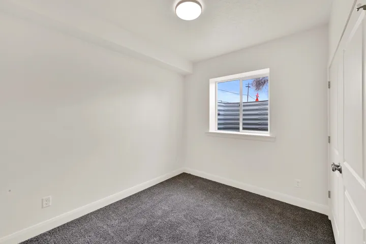 Room featuring neutral wall paint, gray carpet flooring, a single window, and a flush mount ceiling light