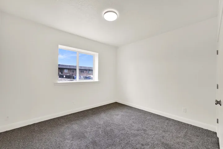 Room featuring a double-pane window, neutral white walls, dark gray carpeting, and white baseboards