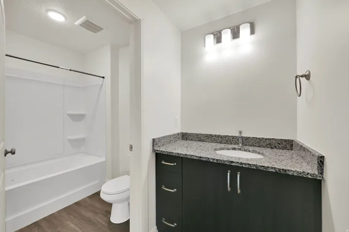 Bathroom featuring a dark wood-finish vanity with a granite-style countertop, undermount sink, and brushed nickel hardware