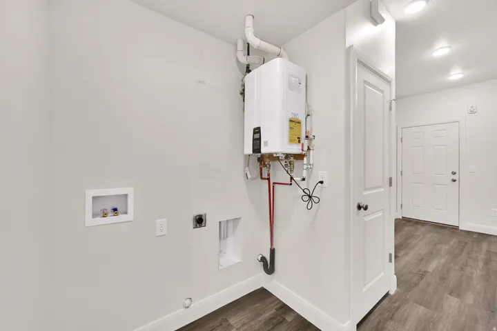 Dedicated utility area featuring a tankless water heater, laundry hookups, and wood-finish flooring