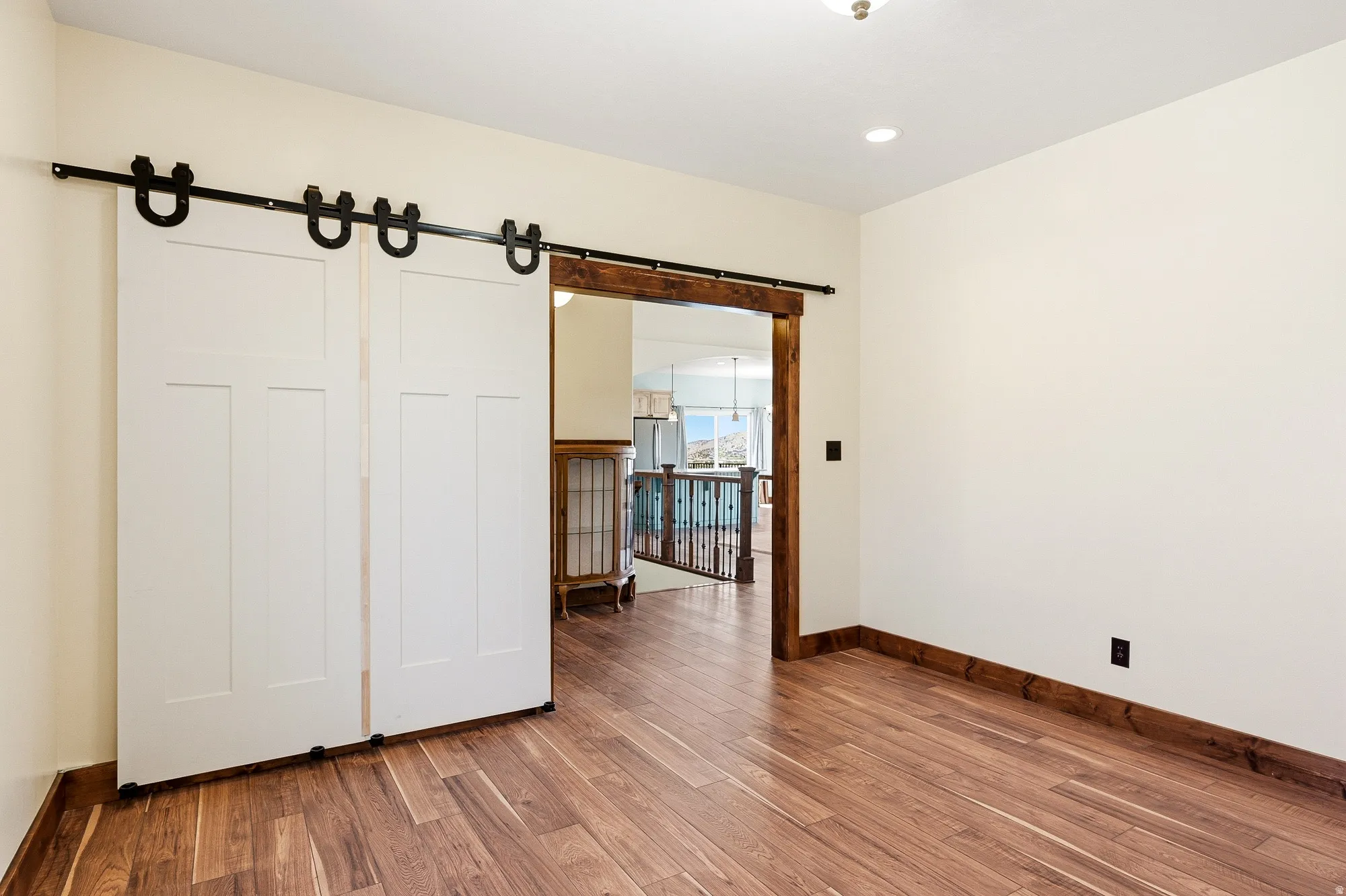 Room featuring wood-finish flooring, white walls, and recessed lighting