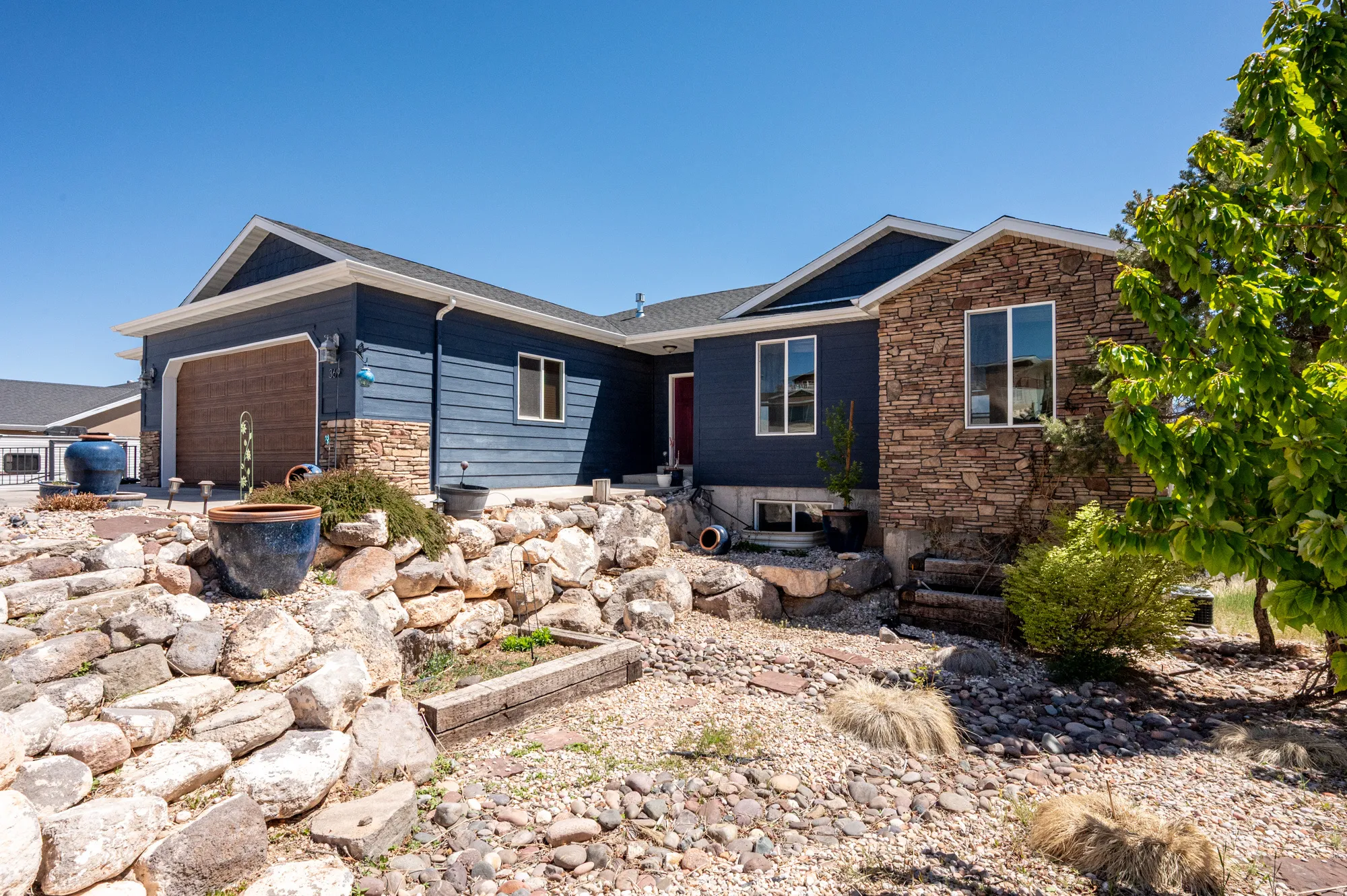 Contemporary exterior featuring horizontal siding in a deep blue hue with stone accents