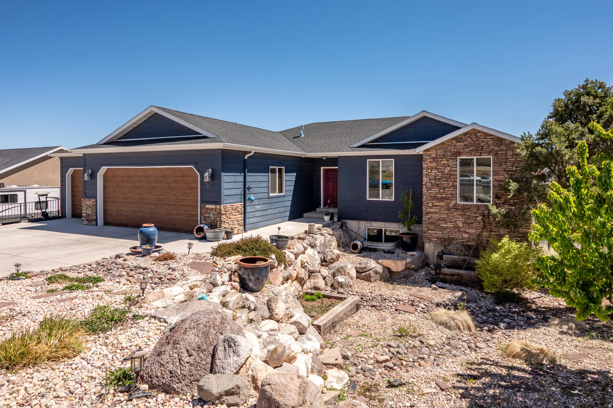 Contemporary residence featuring a dark blue siding exterior with natural stone accents