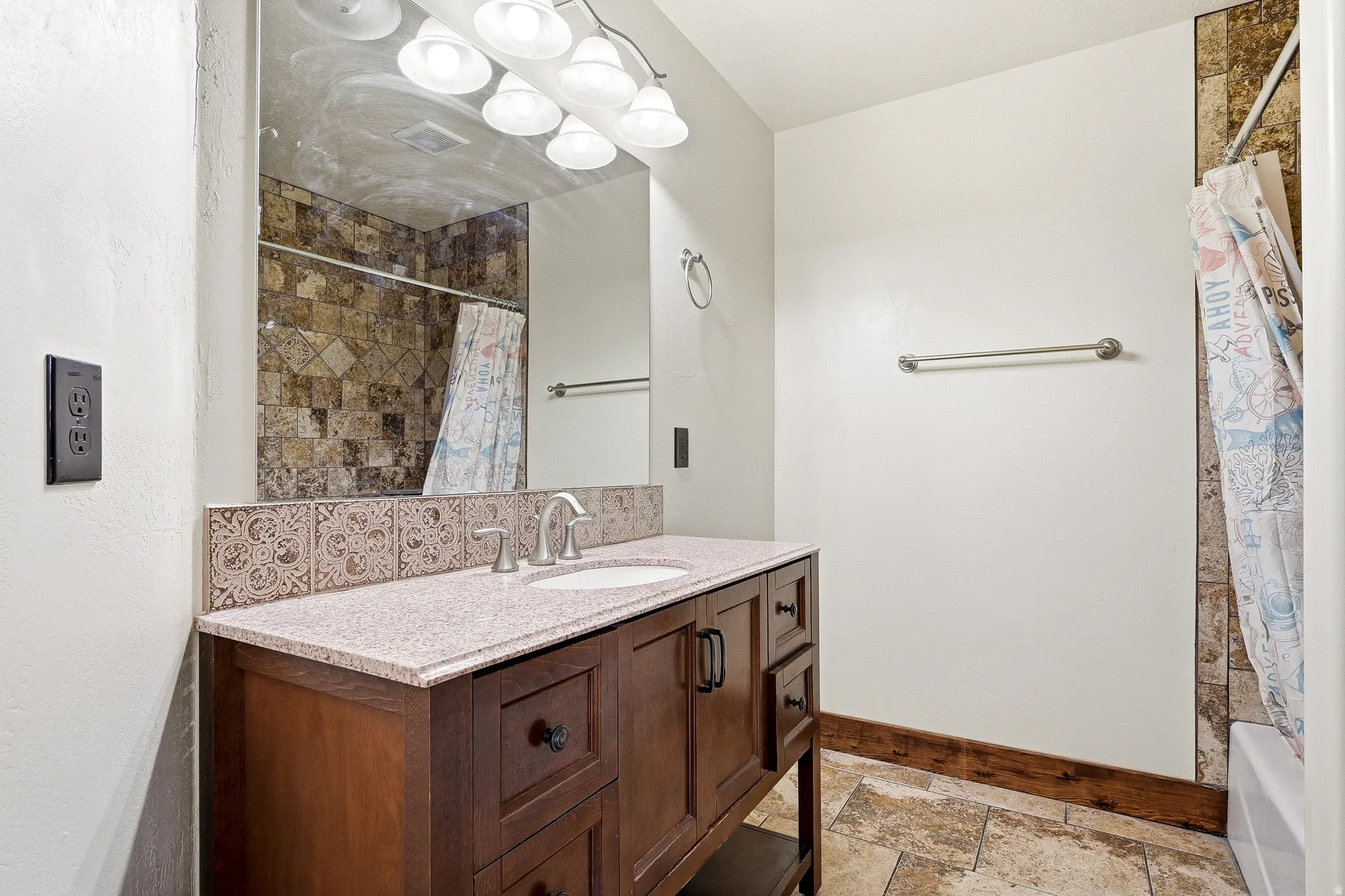 Bathroom vanity featuring a single basin, light-toned countertop, and dark wood-finish cabinetry