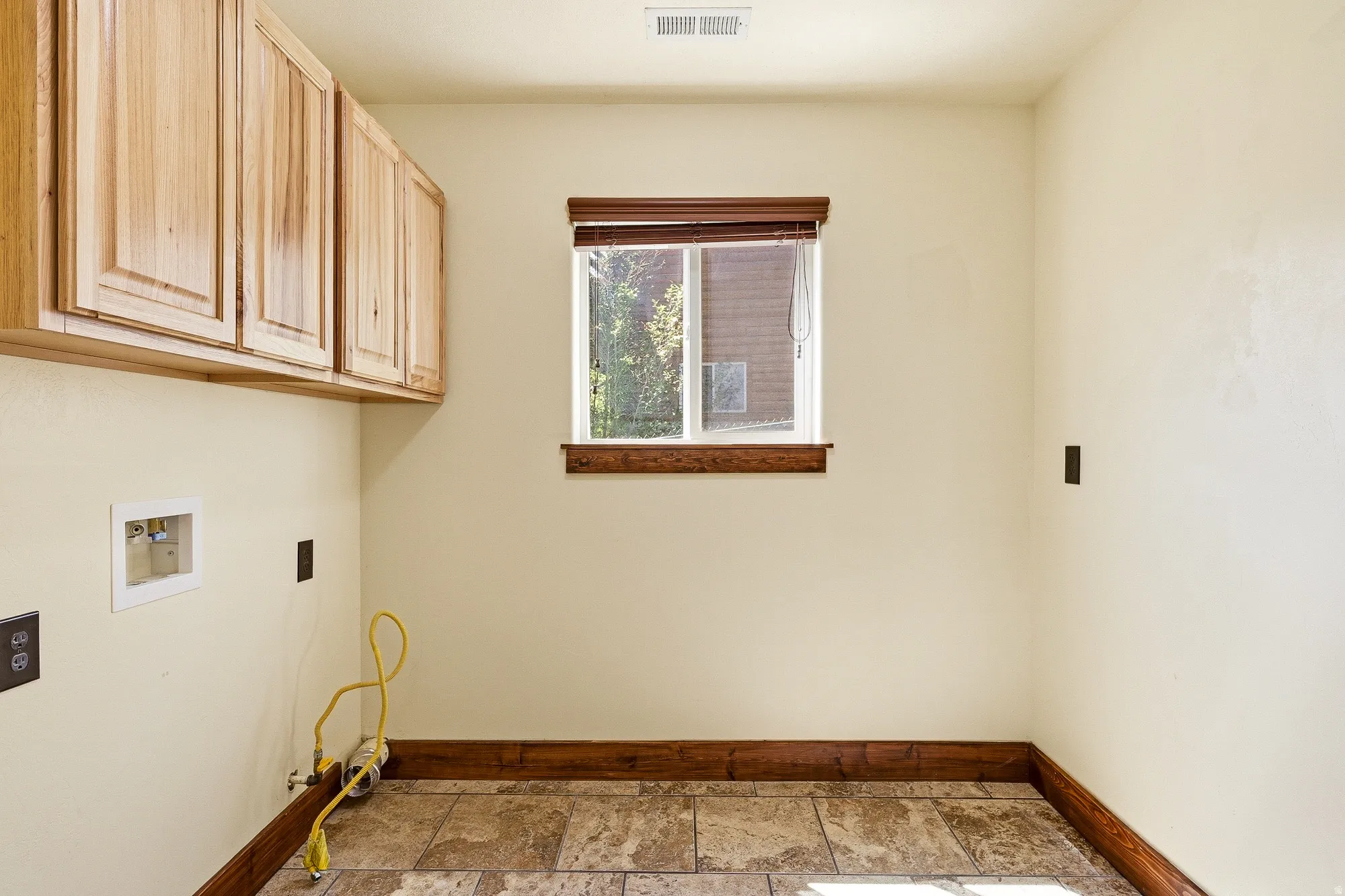 Utility room with natural wood-finish cabinetry and tile flooring