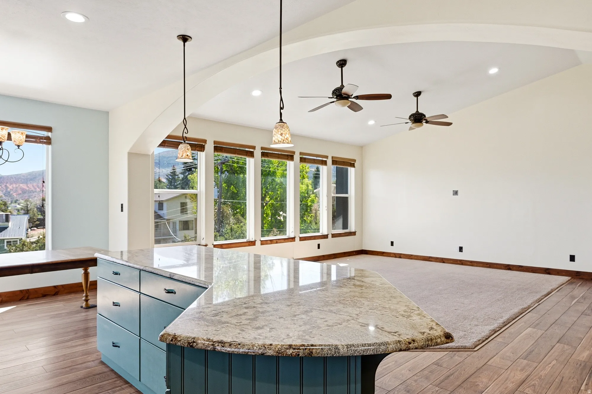 Open-concept living area featuring a kitchen island with stone countertop, ample cabinetry, and pendant lighting