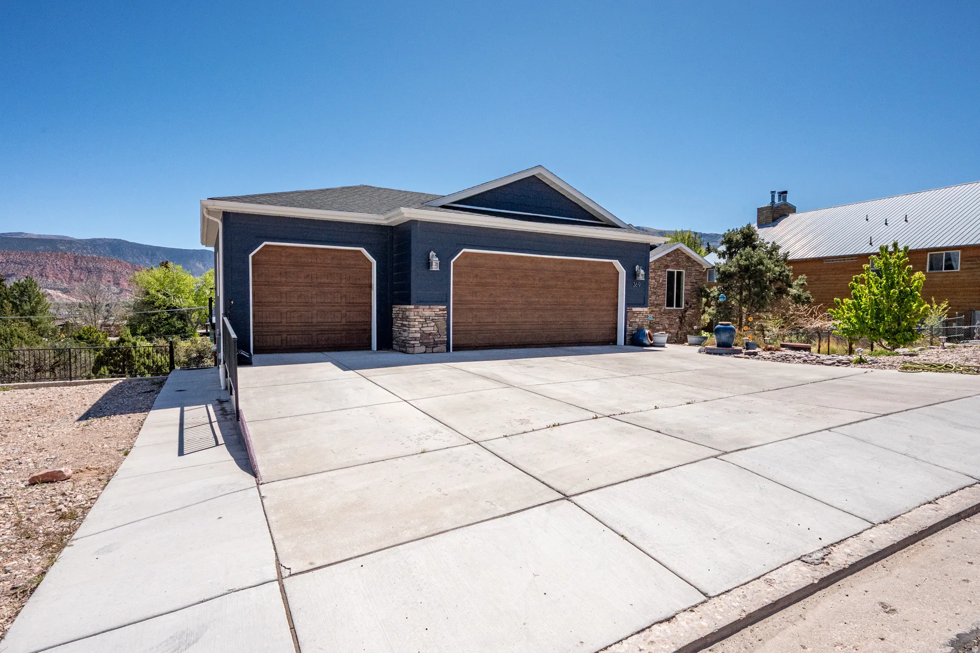 Contemporary exterior featuring dark blue siding and a prominent two-car garage with wood-finish doors