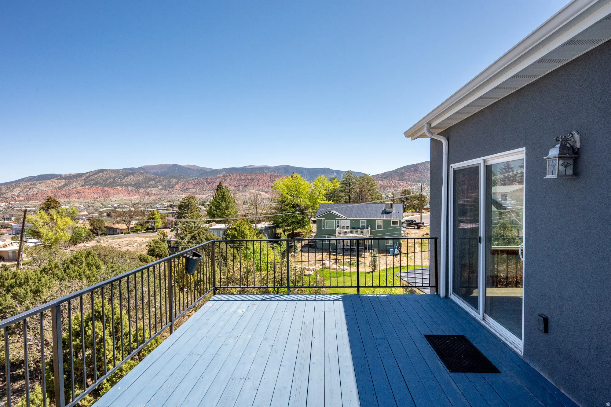 Expansive outdoor deck featuring blue-painted wood flooring and black metal railings