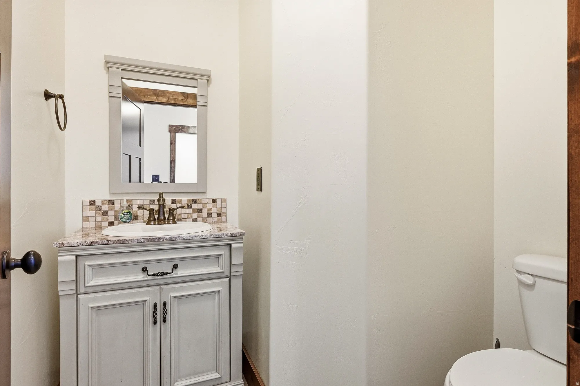 Bathroom vanity featuring a light-toned cabinet, integrated sink, and an elegant mosaic tile backsplash