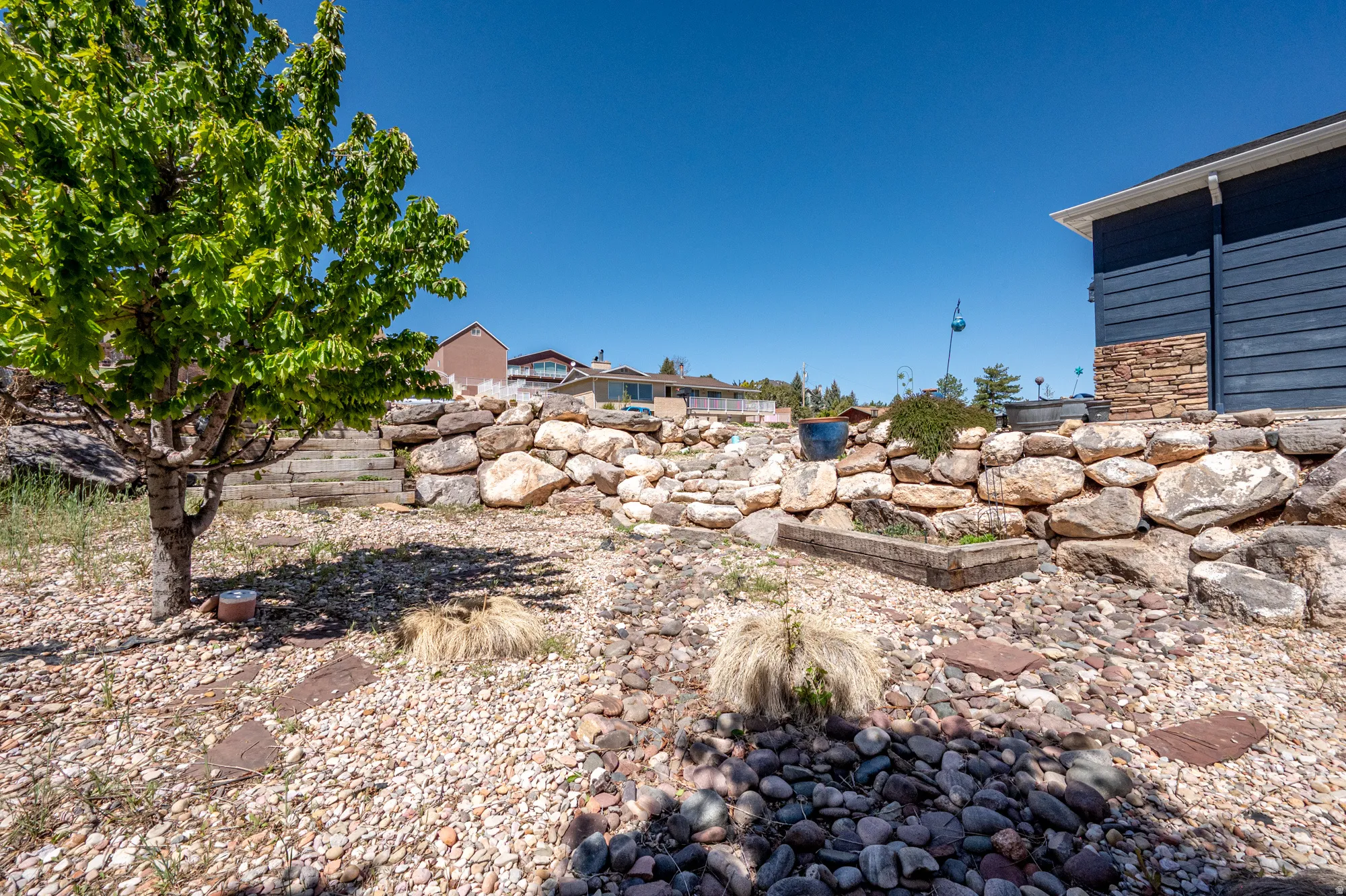 Multi-level landscaping featuring a stone retaining wall and varied gravel ground cover