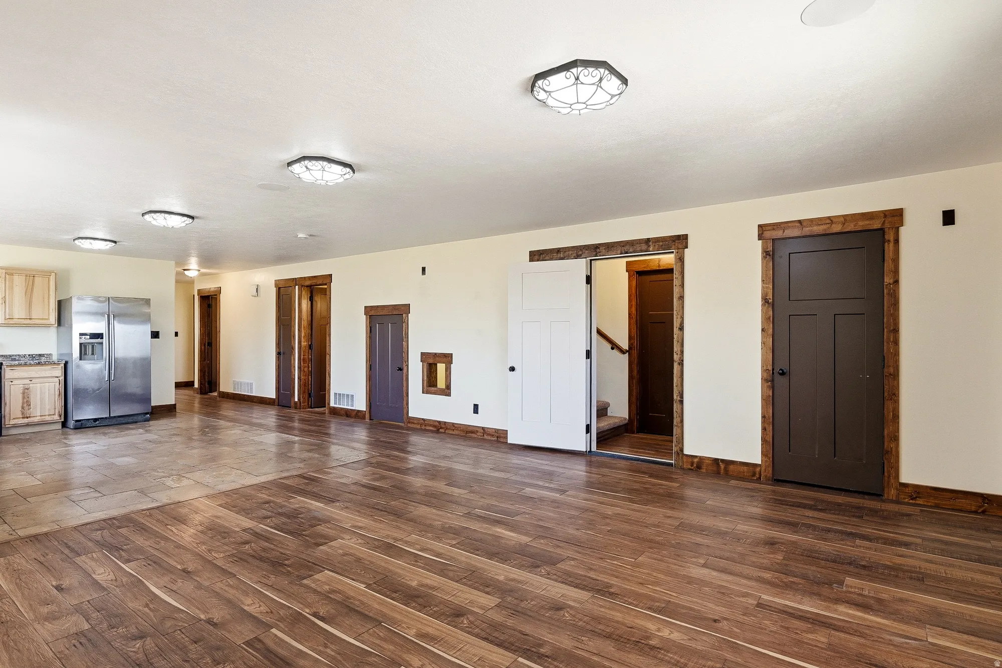 Spacious interior featuring a combination of wood-finish and tile flooring, recessed and flush-mount lighting, and natural wood trim