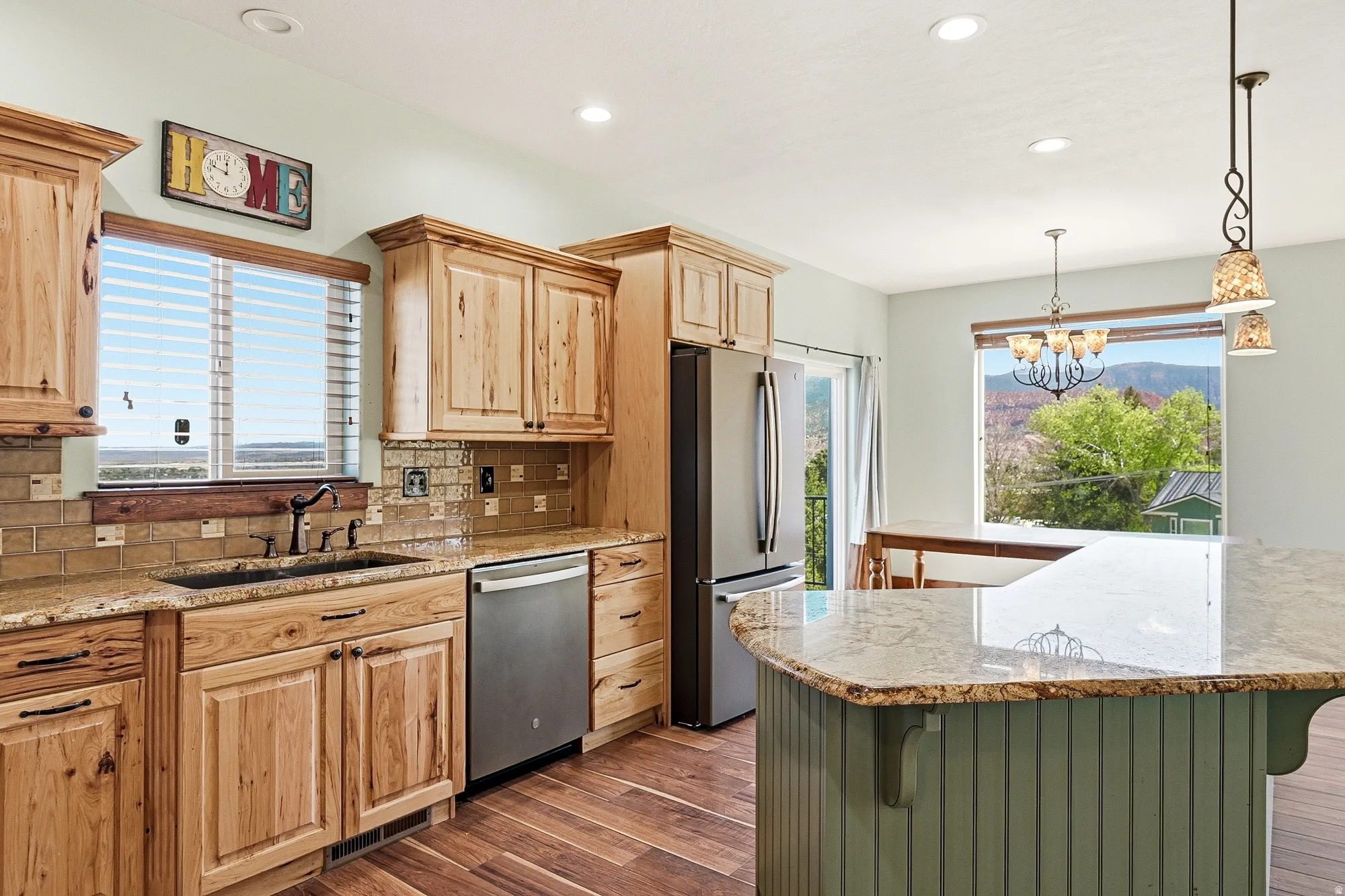 Kitchen featuring natural wood cabinetry, light-toned granite countertops, stainless steel appliances, and wood-finish flooring