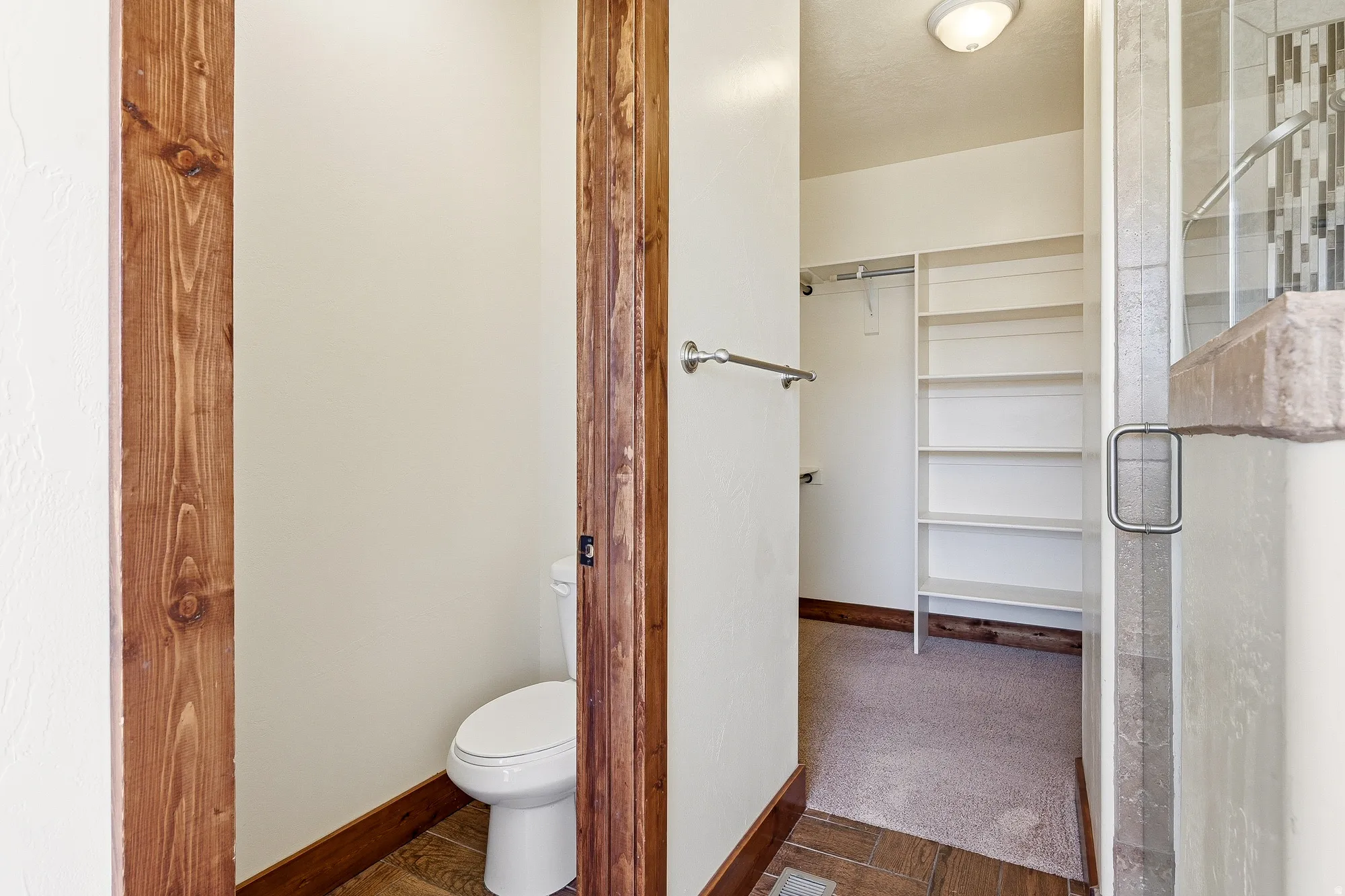 Private water closet featuring a standard toilet and wood-finish flooring