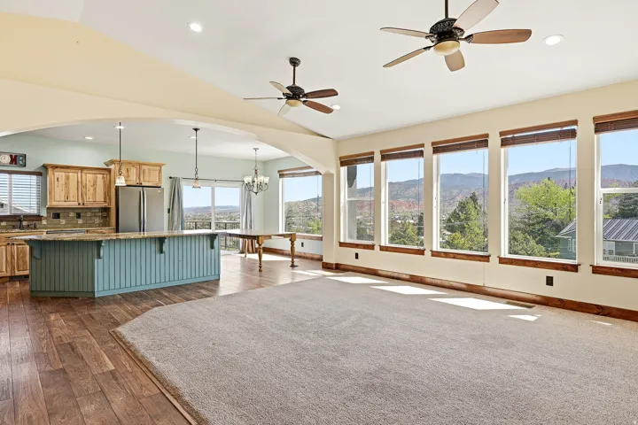 Open-concept living area featuring wood-finish flooring, a kitchen island with beadboard paneling, and a wall of windows
