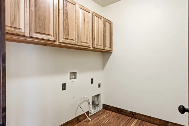 Utility area featuring wood-finish flooring, light-toned walls, and abundant upper cabinetry
