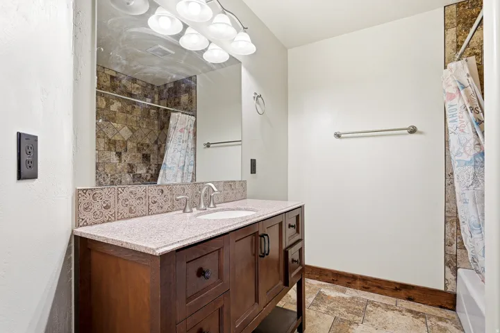 Bathroom vanity featuring a single basin, light-toned countertop, and dark wood-finish cabinetry
