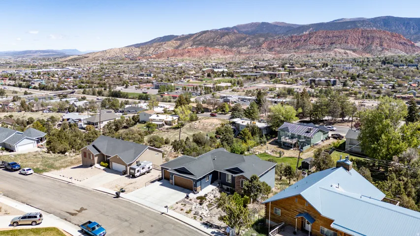 Residential street featuring multiple single-story homes, concrete driveways, and mature landscaping