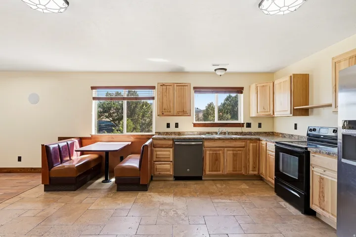 Spacious kitchen featuring natural wood cabinetry, dark granite-look countertops, and stainless steel appliances