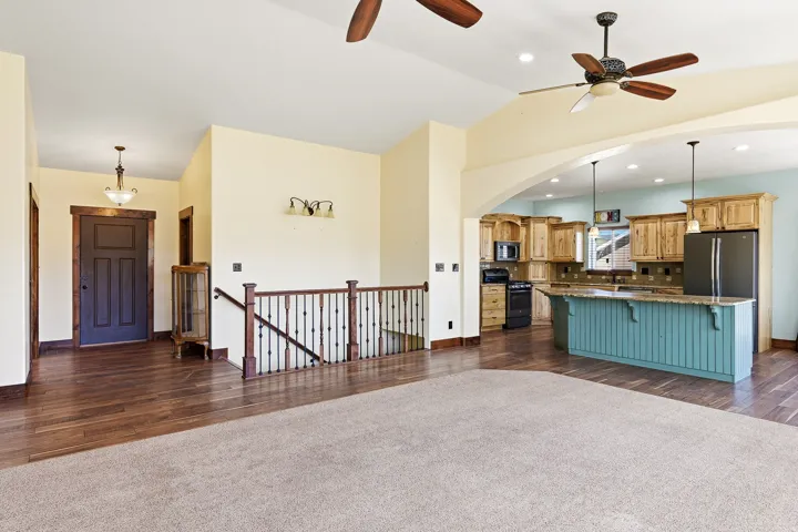 Open concept living area featuring a kitchen with light wood cabinetry, a turquoise island with beadboard paneling, and pendant lighting