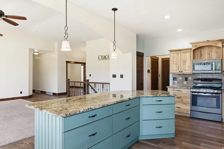 Spacious kitchen island featuring a granite countertop and teal cabinetry with black hardware