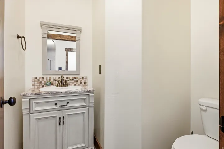 Bathroom vanity featuring a light-toned cabinet, integrated sink, and an elegant mosaic tile backsplash