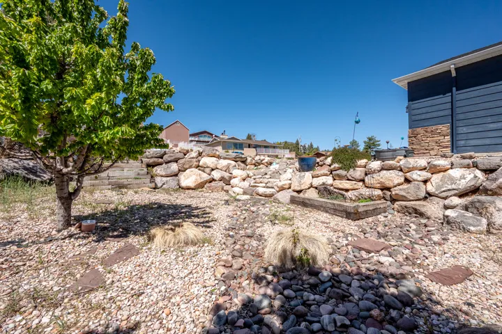 Multi-level landscaping featuring a stone retaining wall and varied gravel ground cover