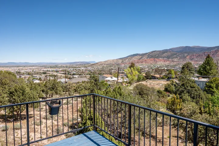 Balcony with metal railing and a multi-layered distant landscape featuring mountains and city buildings