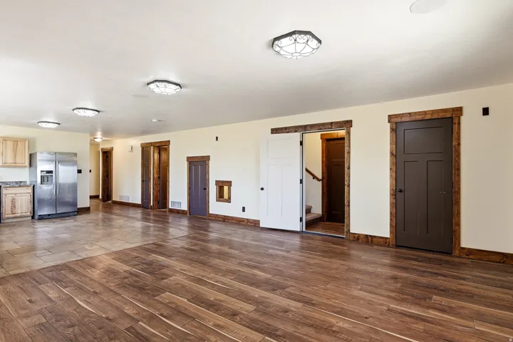 Spacious interior featuring a combination of wood-finish and tile flooring, recessed and flush-mount lighting, and natural wood trim