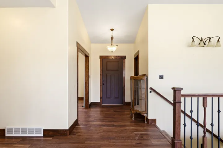 Entryway with wood-finish flooring, dark wood trim, and a dark paneled door