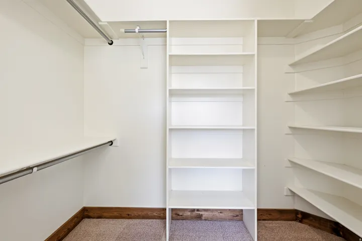 Walk-in closet featuring built-in shelving, hanging rods, and corner shelving units