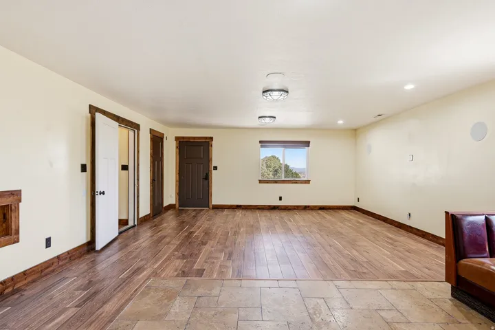 Spacious room featuring wood-finish flooring transitioning to large format tile