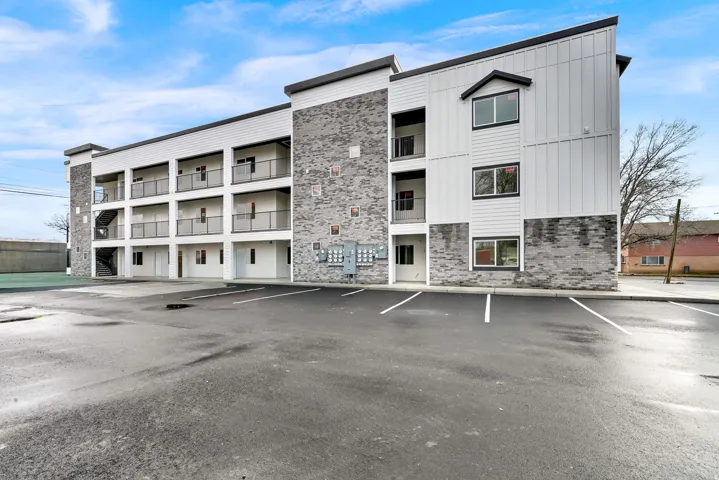 Contemporary multi-story building featuring a blend of white horizontal siding and gray stone veneer