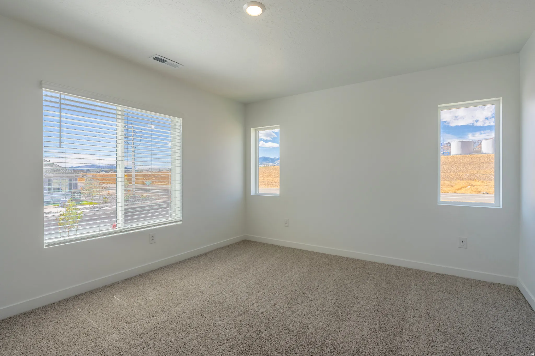 Recessed lighting, light-toned carpeting, multiple windows with blinds, and white wall finishes