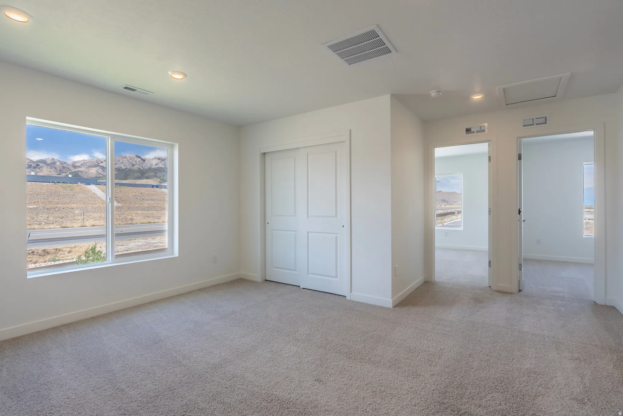 Spacious room featuring neutral carpet flooring, a large window, and a bi-fold closet door