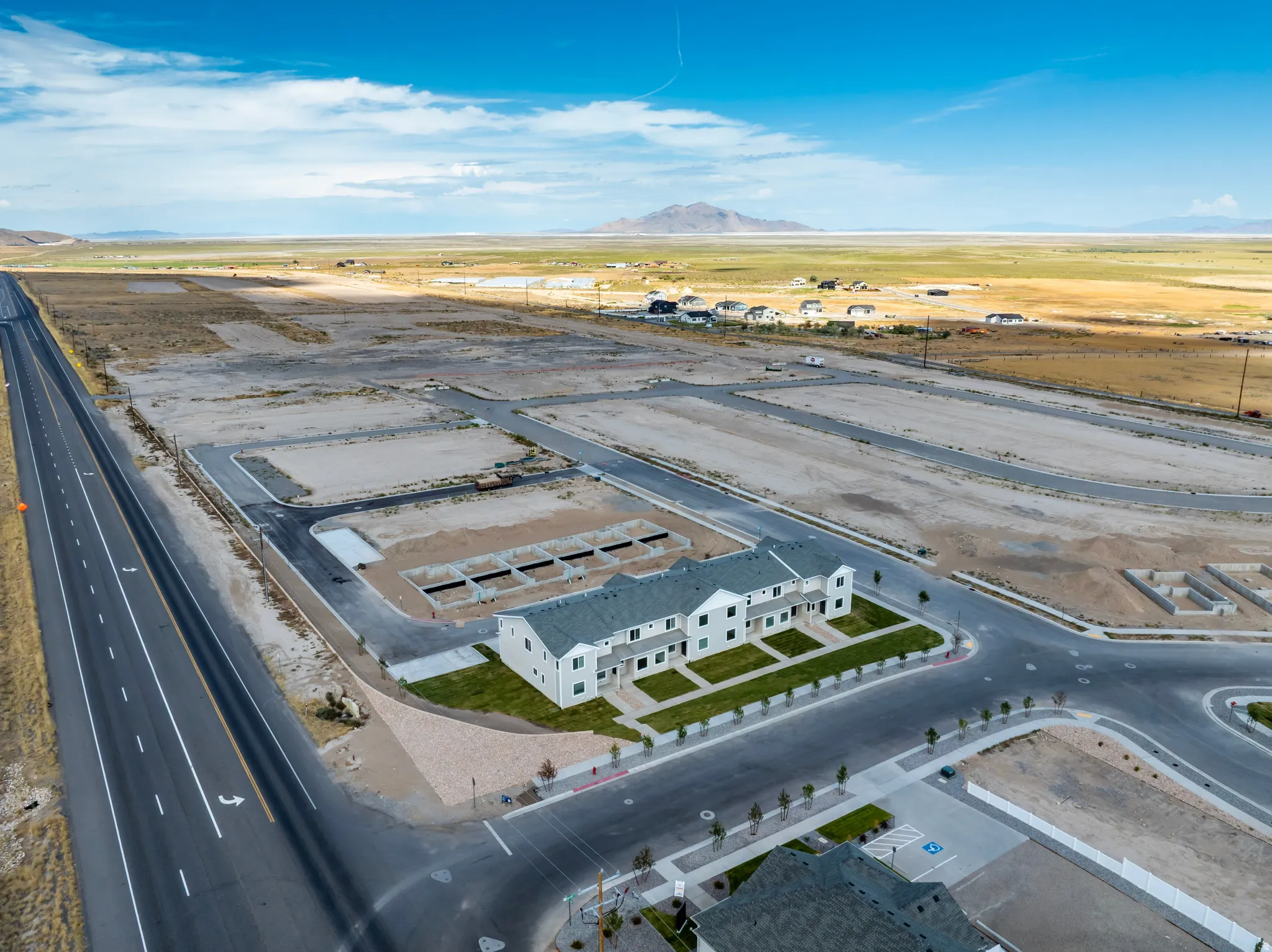 Modern townhome construction with multiple units, manicured green spaces, and paved roadways