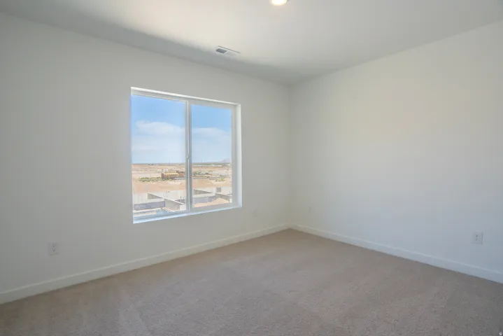 White walls, light-colored carpeting, and a large window
