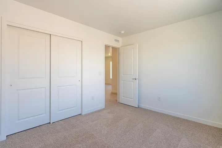 Carpeted room with white walls, a white paneled door, and a two-panel sliding closet