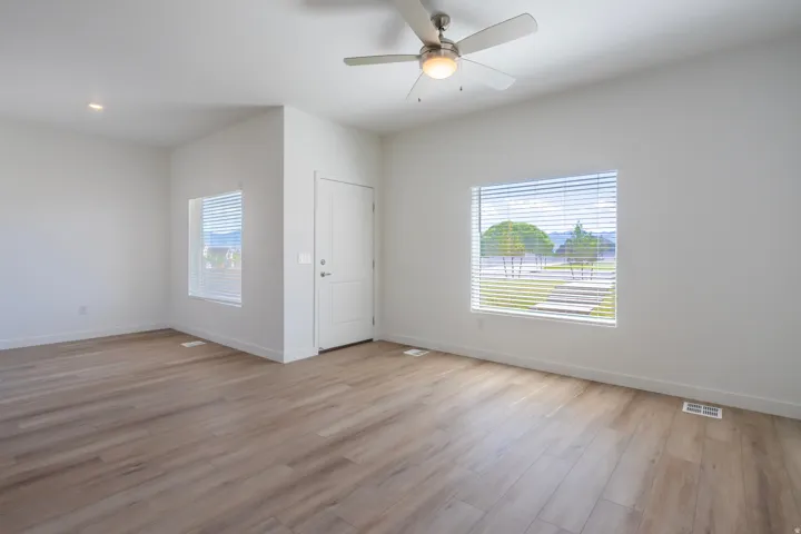 Wood-finish flooring throughout, modern ceiling fan with integrated lighting, recessed lighting, and white interior door