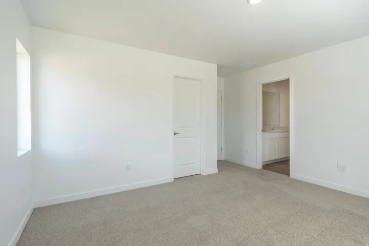 Neutral tone paint, carpeted flooring, window, recessed lighting, and an entryway to another room