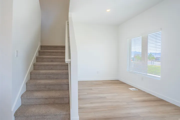 Carpeted staircase, wood-finish flooring, recessed lighting, and large windows with blinds