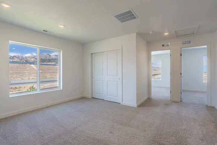 Spacious room featuring neutral carpet flooring, a large window, and a bi-fold closet door